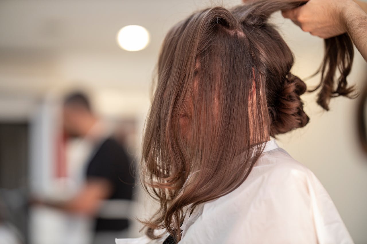 Side view of a woman getting hair styled by hairstylist in a modern salon setting.